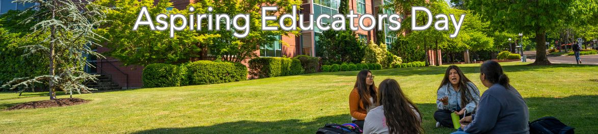 A group of four students sitting on the grass in front of a campus building, talking and laughing together under the shade of trees. Text overlay reads 'Aspiring Educators Day'."